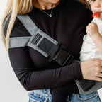 Parent carrying toddler in the Lux Graphite wipeable hip carrier