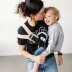 Parent carrying toddler in the Sand Beige Rouu Baby II hip carrier