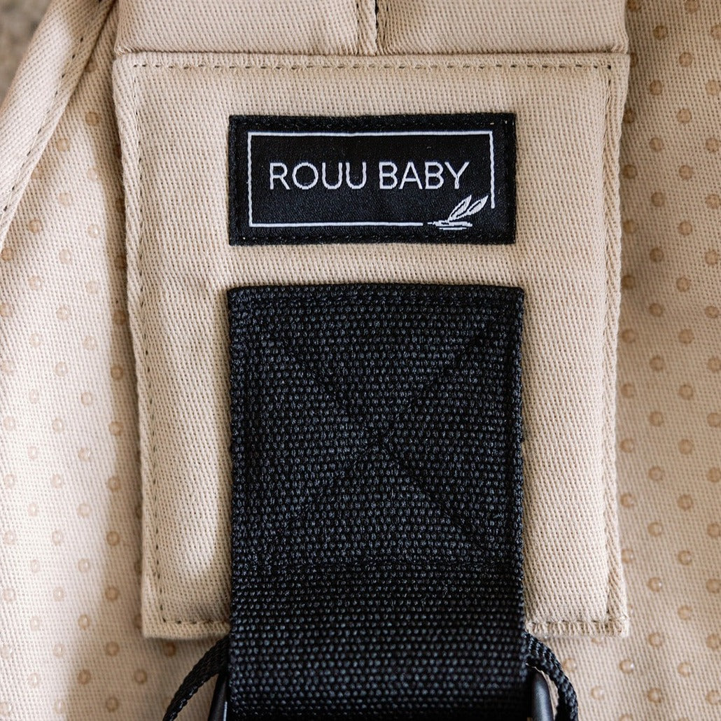 Baby seated in the Sand Beige Rouu Baby II ergonomic hip carrier